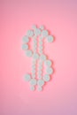 White pills on a pink background. Dollar sign made from white pills Royalty Free Stock Photo