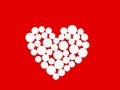 White medicine pills in the shape of a heart on a red background top view with copy space. Royalty Free Stock Photo