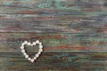 White pills in the shape of a heart on a wooden background Royalty Free Stock Photo