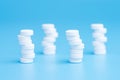 White pills stacked on each other in different positions on blue background Royalty Free Stock Photo