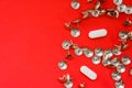 White pills surrounded by sharp thumbtacks at distance from them is on red background with empty area for headers top view. Concep