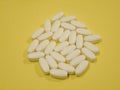 White pills or tablets isolated on soft yellow background. Royalty Free Stock Photo