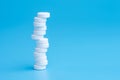 White pills or tablets stacked on each other in different positions on blue background Royalty Free Stock Photo