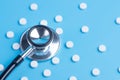 White pills or tablets and stethoscope on blue background Royalty Free Stock Photo