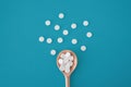 White pills on wooden spoon on a blue background Royalty Free Stock Photo