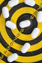 White pills on yellow and black dart target