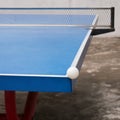 White pingpong ball hits the corner of blue pingpong table