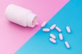 White pink and blue pill. Macro photo pills that pour out of a white bottle on a pastel colored background Royalty Free Stock Photo