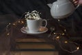 A white and pink colours porcelain tea cup and a spoon on three ancient books with gypsophila flowers in it, close up, still life Royalty Free Stock Photo