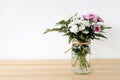 White and pink daisy bouquet in mason jar on table background