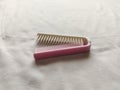 white and pink folding comb with a white background