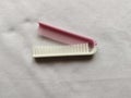 white and pink folding comb with a white background