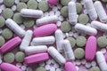 White, pink and green pills on a pink background. multi-colored drugs.