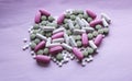 White, pink and green pills on a pink background. multi-colored drugs.