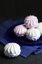 White and pink marshmallow on blue plate on black background Royalty Free Stock Photo