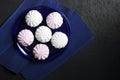 White and pink marshmallow on blue plate on black background Royalty Free Stock Photo