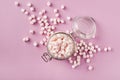 White and pink marshmallows in glass jar on pink background