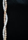 White and pink pearls on the black silk background Royalty Free Stock Photo