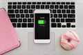 white pink phone with charged battery screen on notebook keyboard Royalty Free Stock Photo