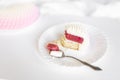 A white-pink piece of cake lies on a white plate on a light background. Royalty Free Stock Photo