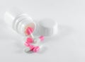 The white-Pink pills spilling from a white plastic bottle on white b Royalty Free Stock Photo