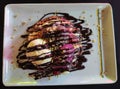 White and pink sweet ice cream with fruit and chocolate topping on baked waffle, on a white plate on the table in a cafe Royalty Free Stock Photo