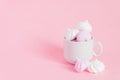 White and pink twisted meringues in a small porcelain coffe cup on pink background. French dessert prepared from whipped with Royalty Free Stock Photo