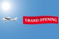 White plane with a banner grand opening in the sky Royalty Free Stock Photo