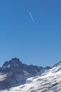 Plane contrails contrast jagged ridge leading to Mount Rainier