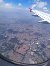 White plane wing with red tip and city view from above with a blurred from the plane window and with the blue sky and clouds Royalty Free Stock Photo