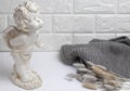 White plaster figurine of an angel against a brick wall with a knitted gray scarf and dried flowers hare tails. Royalty Free Stock Photo