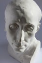 White plaster statue of mans head on blue grey background