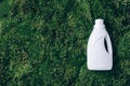 White plastic bottle of cleaning product, household chemicals or liquid laundry detergent on green grass, moss Royalty Free Stock Photo