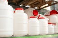 White plastic cans with red lids on a rack stillage