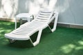 White plastic chair, chaise lounge on the grass with table. Background with copy space. Concept of free time, vacation Royalty Free Stock Photo