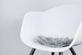 Side view of a modern white plastic chair with a seat cushion made of grey artificial long fur, use as design background for Royalty Free Stock Photo
