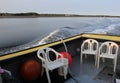White plastic chairs sitting in the back of a yellow and black fishing boat on the calm waters of a bay in Nova Scotia Royalty Free Stock Photo