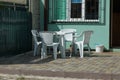 White plastic chairs and a table stand on a gray sidewalk