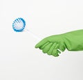 White plastic cleaning brushes in hand, protective green glove on hand
