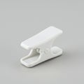 A white plastic clip with a flat, rectangular gripping surface and a rounded hinge. It has Royalty Free Stock Photo