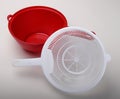 White plastic colander to red bowl Royalty Free Stock Photo