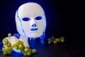 Color therapy mask glowing blue with grapes