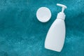 White plastic cosmetic bottle with dispenser and cotton pads on aqua color background. Concept of skin care of face Royalty Free Stock Photo