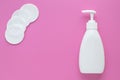 White plastic cosmetic bottle with dispenser for skin care of face. Cotton pads on pink background and cleanser, makeup remover. Royalty Free Stock Photo