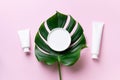 White plastic cosmetic jar, tube, bottle and tropical monstera leaf over pink background. Top view. Flat lay. Mock-up. Cosmetics, Royalty Free Stock Photo