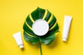 White plastic cosmetic jar, tube, bottle and tropical monstera leaf over yellow background. Top view. Flat lay. Mock-up. Cosmetics Royalty Free Stock Photo