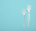 White plastic cutlery for picnics on a blue background. Disposable spoon, fork. Top view, copy space Royalty Free Stock Photo