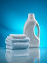 White plastic detergent bottle and neatly folded light blue and white towels reflecting on a shiny surface against a vibrant blue Royalty Free Stock Photo
