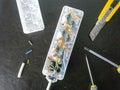 White plastic electric extension socket internal circuits with knife, screwdrivers and removed wire insularion top view