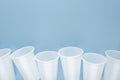 White plastic empty cups laid out in a row on blue background. Royalty Free Stock Photo